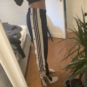 Adidas byxor  - Adidas byxor som man kan knäppa upp på sidan av byxorna! Så sköna. Lite slitna/noppriga, små fläckar(se tredje bilden på noppret) men annars i fint skick 