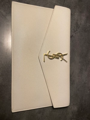 Ysl clutch - Uptown pouch in grain de poudre embossef leather benvit clutch från ysl orginalpris är 490€.  använd tre gånger. äkthesbevis kan skickas. förpackningslåda är inkluderat.