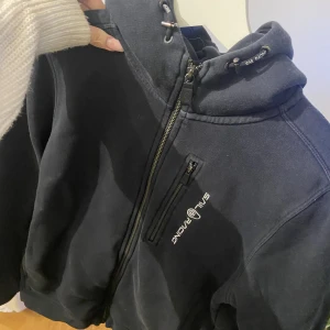 Sail racing hoodie  - Zip up hoodie Sail racing, blivit urtvättat och har en tråd som sticker ut längst ner vid dragkedjan och är nopprig på insidan annars hittar jag inga mer skavanker❤️
