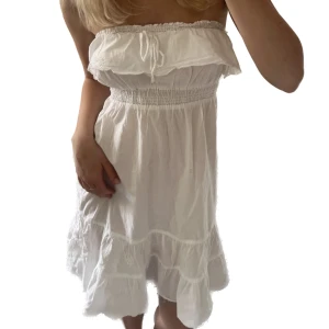 Somrig volangklänning - Vit axelbandslös/bandeau - klänning med volanger. Hur söt som helst och perfekt till både vardags och festligare tillfällen såsom student eller skolavslutning.💘 Storlek M men passar även mig som har XS-S då det är resår i midjan och över bröstet. 
