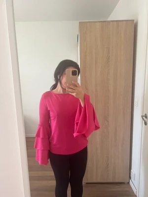 Rosa blus med volanger  - Säljer en rosa blus med volang ärmar! Använd ny skick. Storlek S, bekväm och perfekt längd. Pris: 150 kr + frakt! Skriv för intresse! 