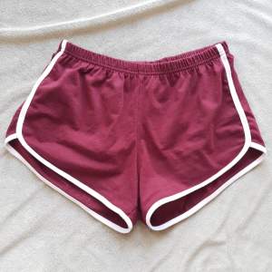 Korta mörkröda shorts med vita detaljer på sidorn. Mjuka och sköna. Använda ett fåtal gånger men inte slitna på någit sätt.