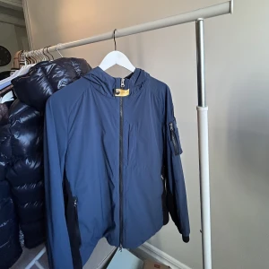 Blå vindjacka från parajumper - Säljer nu min väldigt fina helt oanvända blåa vindjacka från parajumper som jag fick i födelsedagspresent på min 18 års dag nydligen. Säljer denna fina jacka för jag ej använt den och redan har så många jackor!  Storlek: M Pris: 1000