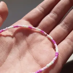 Ett armband med små rosa, vita pärlor. Tips var försiktig det KAN kanske gå sönder!🤗