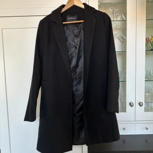 Svart kappa, Stradivarius, storlek S - Säljer en sparsamt använd kappa från Stradivarius. I jättefint skick. Kappan är rak och går ner till knäna :) 