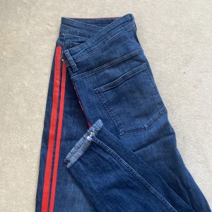 Striped jeans från Zara - Mörkblåa jeans med röda ränder. Från Zara Basic Denim Collection. Jeansen är i gott skick!