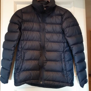 Marinblå Peak performance jacka i storlek S - Marinblå peak performance jacka i storlek S. Använt sparsamt och är i väldigt fint skick.  Har något litet märke vid ena bystet som man kan se på bild 2 men som är minemalt och inget man tänker på. Perfekt som höst och vinterjacka!