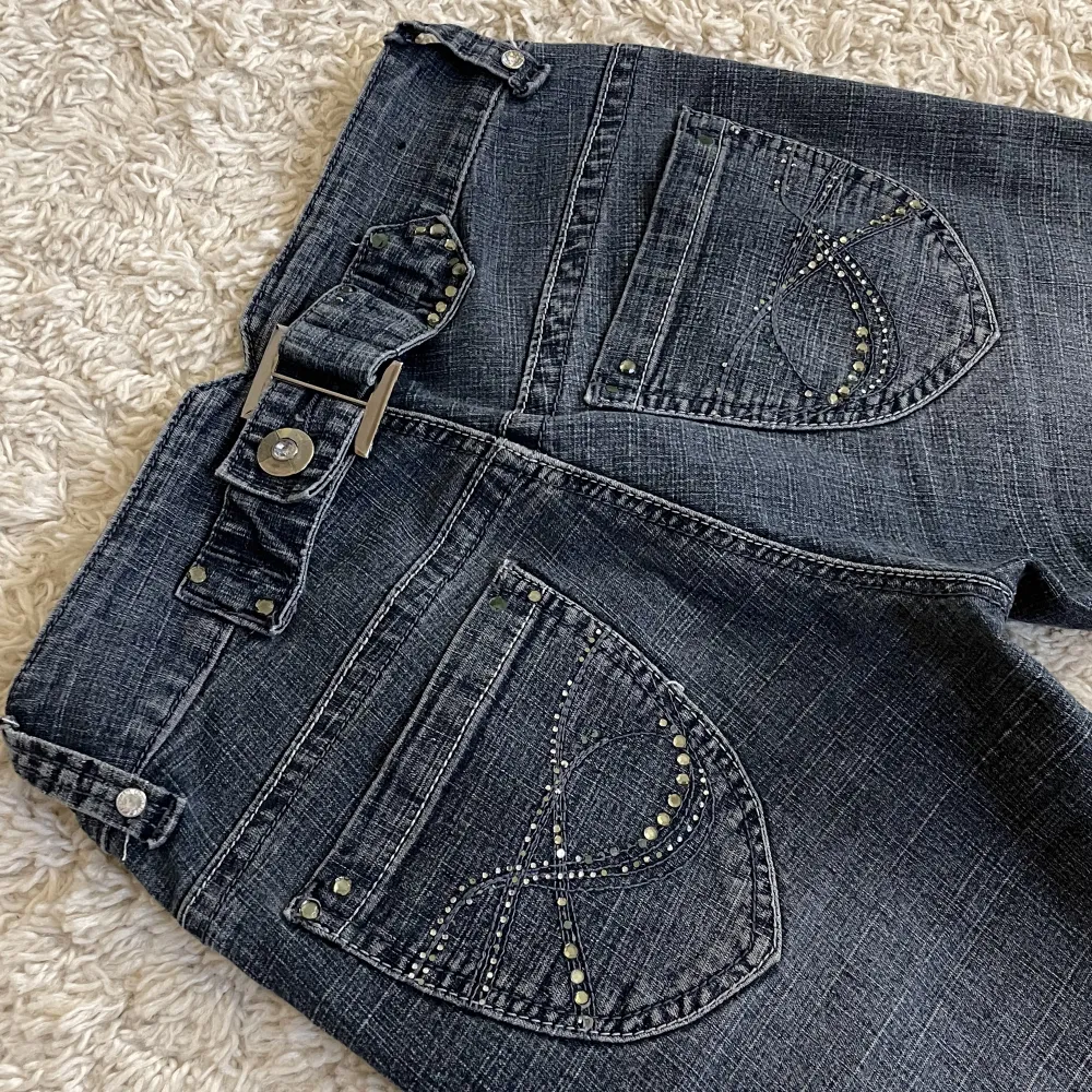 Rhinestones både bak och fram (en del har lossnat) och assnyggt spänne! ❤️Bootcut och lågmidjad modell, gråblå färg. 🫶Innerben: 76cm, midja rakt över: 33cm. Stretchiga!! Jag är 165, kan fixa fler mått. 🥰 Håll koll på min profil, lägger upp vintage jeans. 😍. Jeans & Byxor.