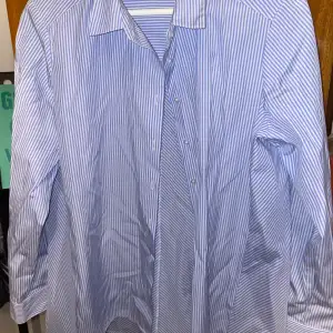 Blå/vit randig skjorta från Hampton Republic. Har ärvt, oanvänd från mitt håll. Inga skador eller fläckar, väldigt bra skick. Fint och bekvämt material. 