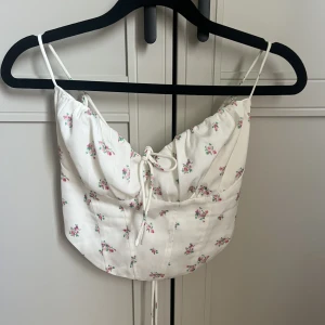 Söt topp - Vit topp med blommor på och knytning i ryggen. Aldrig använd