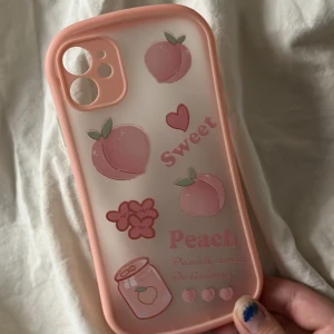 Persika mobilskal för iPhone 11 - Säljer ett jättegulligt mobilskal med massa persikor på (^^) köpt på kawaii shop för några år sedan och nästan aldrig använt. Passar för iPhone 11!