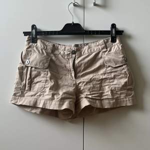 Beiga shorts från märket Brooks Brothers. Fickor med knapp finns på shortsens sidor. 🙌