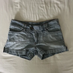 Lågmidjade jeansshorts  - Skit snygga vintage ljusblå lågmidjade jeansshorts med unika bakfickor. Begagnat skick, men inga fläckar eller hål! Midjemått mätt rakt över: 40cm, längd: 28. Storlek 38 men passar även 36🫶💕 