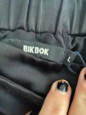 Kjol svart satin  - Svart satin omlott volang 