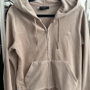 Juicy Couture Helt set - Säljer detta sett då det blivit för stort på mig och inte kommer till användning längre. Den är i färgen Warm Taupe. Detta sett köptes på Juicys egna hemsida för 2300kr.  Enda skadan är att ena metall skyddet på snöret på koftan är borta . Kvitto finns.  