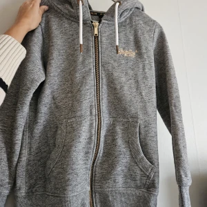 Superdry hoodie - Hoodie med dragkedja från superdry. Tjockt och skönt material perfekt inför hösten! Stl 38 men sitter även fint som lite oversized för stl 34-36