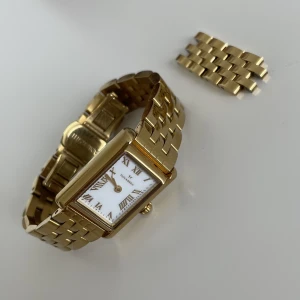Mockberg Timeless Gold Klocka - Mockberg Timelss Gold klocka i väldigt bra skick. Har förkortat länkarmbandet, fullt möjligt att förlänga till ordinarie storlek.  Guldpläterat rostfritt stål med vit urtavla, urtavlans diameter: 19x28 mm. Box medföljer inte, kvitto finns.