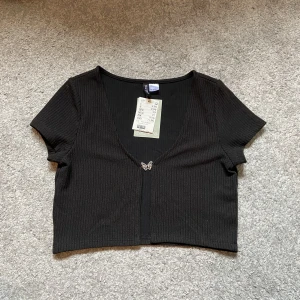 Butterfly top - Räfflad blus/tröja med en silvrig fjäril som knapp