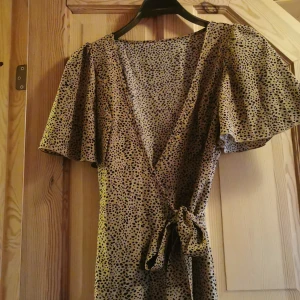 Beige/brun klänning  - Beige/brun klänning med svarta prickar. Helt oanvänd. Nysick. Sitter som en S/M men går att spänna i midjan. 