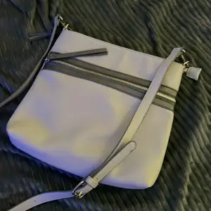Säljer en riktigt fin mellan modell väska märke Orsay färg ljusgrå och mörkgrå med justerbar axelrem i mjukt material 