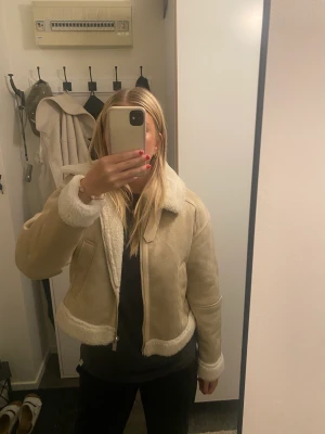 Jacka Zara - Hej!! Säljer denna beiga jacka från Zara. Använd 2-3 gånger max så den är i väldigt bra skick. Fluffig på insidan och med två fickor i sidan. Storlek M