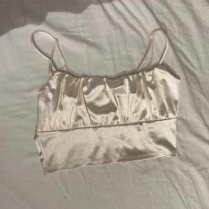 Satin topp  - Säljer denna snygga ish cremevita toppen. Säljer pågrund av att den endast har använts vid något enstaka tillfälle. Den är i storlek M men psssar även också en S.