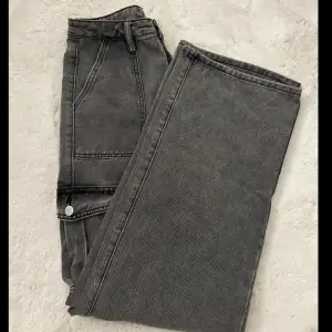Gråa cargopants i jeans material. Dessa är väldigt högmidjade, skriv om ni vill ha fler bilder🫶🏼Storlek S, med fina detaljer både bak och på sidorna/fram. Dessa är i nyskick och aldrig använda!