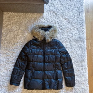 Hollies Jacka - Hollies jacka i strl 42. I väldigt gott skick, dock finns slitage som är vid knapparna till pälsen. Vissa knappar saknas men man kan sy på knappar och så är problemet löst.   Bältet som kom med har jag tyvärr tappat bort.