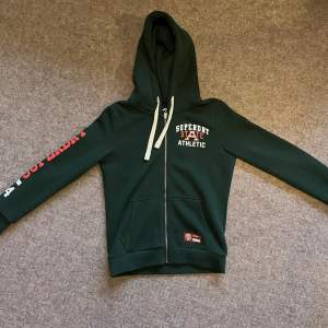 Supersnygg mörkgrön zip-up hoodie från Superdry. Endast använd ca 5 gånger (nyskick). Nypris ca 1000kr mitt pris 500kr (går att diskutera) Storlek 40 men dem är definitivt mer som en 36:a