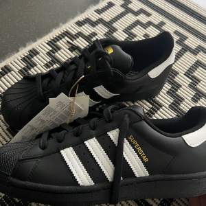 Säljer mina Adidas superstars i svart pga de ej kommer åt användning. Är helt oanvända, köptes detta år! Kartong medföljer. 