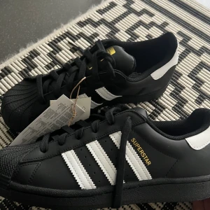 Adidas superstar - Säljer mina Adidas superstars i svart pga de ej kommer åt användning. Är helt oanvända, köptes detta år! Kartong medföljer. 