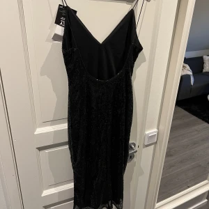 Glittrig klänning  - Aldrig använd klänning med lapparna kvar. Öppen i ryggen och är lite längre i modellen. Perfekt till fest eller nyår 💕
