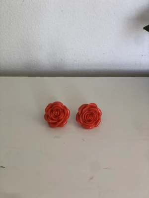 Örhängen - Gulliga lite små chunky örhängen med rosor som motiv. Inte tunga, och inte nickel i dom. Är röda men lutar sig lite åt det orangea nyans slaget! 