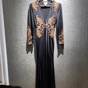 Klänning | Nelly - En jättefin klänning Med gulddetaljer från Nelly. Den har en slit där framme, inte på sidan av klänningen. Det finns även en mini-klänning under för extra säkerhet. Urringningen har även spännen, man kan knäppa och bestämma hur urringat man vill ha. 