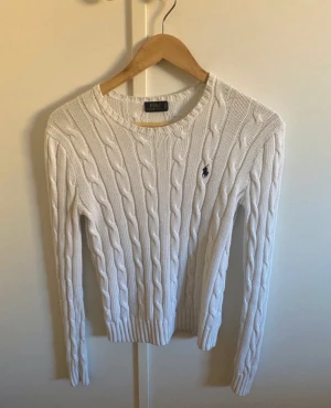 Ralph Lauren vit stickad tröja - Den har 2 defekter fast den syns inte när man har på sig den. Det är bara innuti där den har blivit lite sprättad (se bild) och fått lite blått tvättmedel på sig. Men man ser inte det utanför, annars ser den bra ut. Man märker inte av det när den är på.
