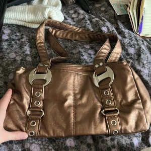 Skimrande väska - Köpt på second hand,  slitningar på undersidan av väskan.