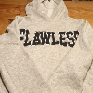 Grå hoodie med text - En grå hoodie med luva och text "Flawless". Från Gina Tricot.