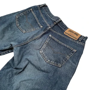 Jack & Jones jeans - Ett par blåa Jack & Jones jeans i fint skick. Lite slitna i nederkant, se sista bilden. Innerbenslängd: 80cm. Midjemått: 90cm. Benbredd lår: 30,5cm. Benbredd smalben: 22,5cm. Vid frågor eller önskemål om fler bilder, skriv privat! 