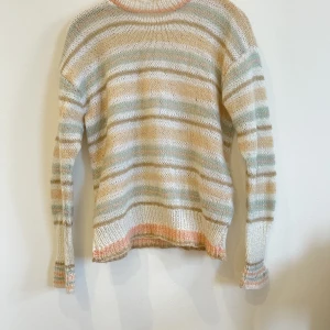 Stickad tröja i ljusa färger - För liten för mig men älskar färgerna! En mindre slitning som syns på bilden i nacken men syns inte när den väl är på.