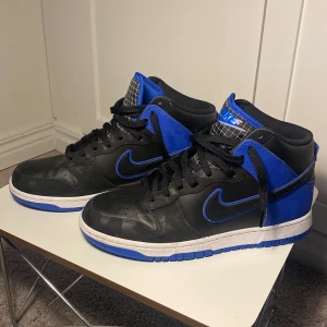 Nike dunk high - som nya - Säljer ett par Nike dunk High i stl 43 - använda ett fåtal ggr, väldigt bra skick. Svarta med detaljer i blått.