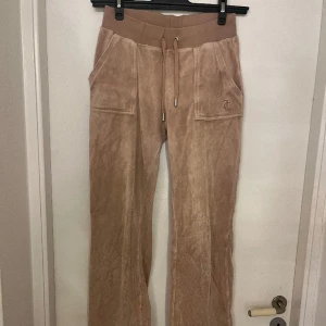 beiga juicy byxor - säljer mina beiga juicy byxor, de är inte i det mjukaste materialet! jättefint skick men säljer billigt pga att dem blivit lite slitna längst ner då dem är för långa på mig!