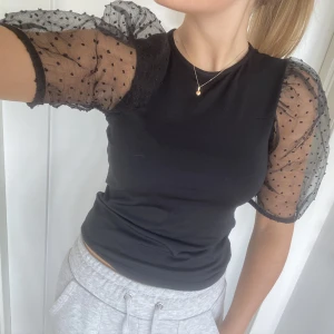 Svart topp - Säljer nu min sjukt snygga topp med genomskinliga puffärmar i stl S. Säljs då den inte används längre.💗 Liten skada på ena armen så pris kan diskuteras.💞