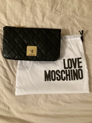 LOVE MOSCHINO VÄSKA  - Svart axelremsväska från LOVE MOSCHINO. Fauxläder, aldrig använd. Höjd 14cm, bredd 23cm. Köparen står för frakt 