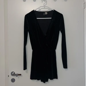 Kort byxdress - Superfin glittrig byxdress i velour med korta ben, resor i midjan och en liten diskret knapp om man vill ha mindre urringning. Jättefin till ett par höga boots/klackar med tunna strumpbyxor under. 