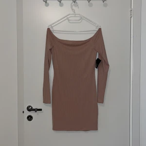 Kort figursydd klänning - Superfin puderrosa figursydd klänning med off-shoulder, 3/4 ärmad. Aldrig använd som ni ser, lapparna sitter kvar!