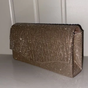 Bal väska  - Denna balväska i färgen guld/champagne och den glittrar väldigt mycket, den har ett band som du kan ha på axeln men även kan du hålla i den🫶🏻även har den plats för mycket och ett litet fack inuti. Endast använd 1 gång,, säljer för 100kr🫶🏻🫶🏻