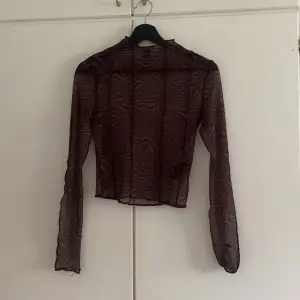 Genomskinlig brun tröja med mönster. 