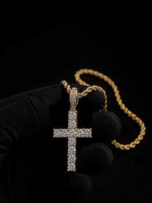 Cordell Halsband Med Diamant Kors - Snyggt halsband i guldfärg med ett korsformat hänge täckt av glittrande stenar. Kedjan har en tvinnad design som ger en exklusiv känsla. Perfekt accessoar för dig som vill sticka ut och addera lite extra bling till din stil.