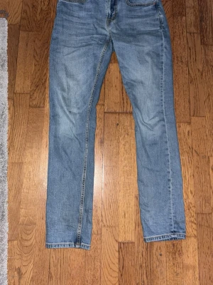 Blå raka jeans med klassisk passform - Säljer ett par blå jeans med rak passform och klassisk femficksdesign. Jeansen har en snygg tvättad look och kontrastsömmar. Perfekta till vardags för en avslappnad stil. Midjan är 31 och längden 32.