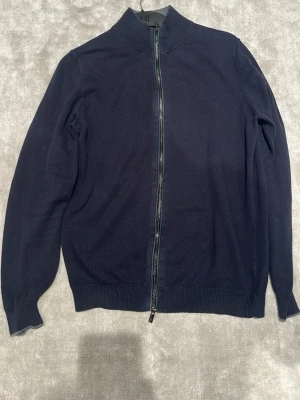 Massimo dutti zip - Snygg mörkblå ziptröja från Massimo dutti med hel dragkedja framtill och hög krage. Tröjan har långa ärmar och ribbade muddar vid ärmslut och nederkant. Perfekt för lager på lager och enkel att matcha med olika outfits.